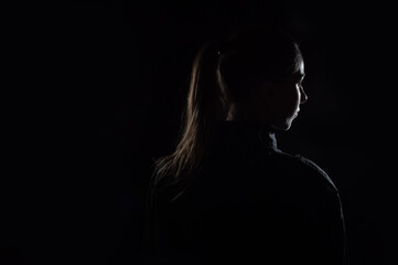 Female person silhouette in the shadow, back lit light