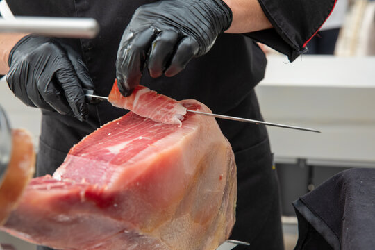 Front view of a professional ham cutter cutting an Iberian ham.
