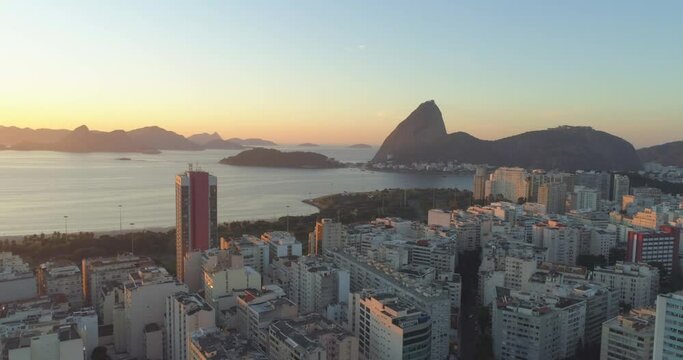 Sunrise tracking aerial of Sugarloaf Mountain and the Guanabara Bay in Rio de Janeiro Brazil over apartment blocks in Flamengo