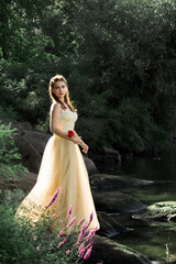 Bright color photo of a beautiful fairytale princess in a yellow ball gown in an old park, holding...