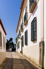 Street of a portuguese city with low white buildings and paving stones on the road