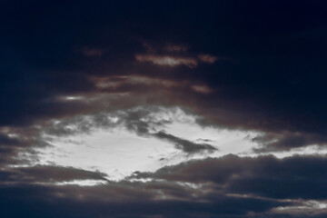 Fototapeta na wymiar Light spot through dark rain clouds storm beam light sky weather background