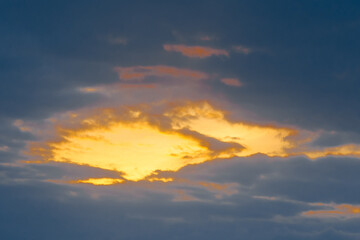 Naklejka na ściany i meble Light spot orange sunset through dark rain clouds storm beam light sky weather background