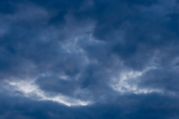 Naklejka na ściany i meble Light spot through dark rain clouds storm beam light sky weather background