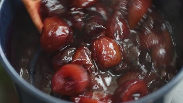 Preparing homemade plum jam in a saucepan.
