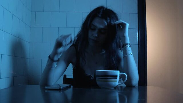 Young woman looking at mobile phone out of boredom and despair at night at home