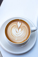 white cup of cappuccino with latte art on white table