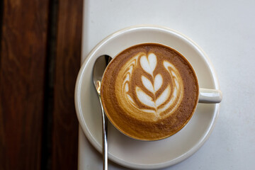 white cup of cappuccino with latte art on white table