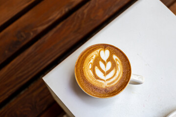 white cup of cappuccino with latte art on white table