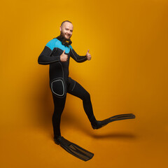 Fototapeta na wymiar Summer vacation, travel and sea rest concept. Happy man wearing scuba diver suit and flippers on yellow background
