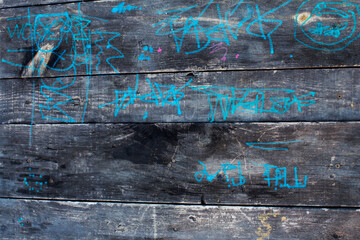 texture of old wooden boards burnt out in the sun with children's inscriptions in chalk