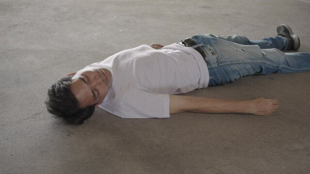 Man lying unconscious on cement floor due to extreme heat, heat stroke, global warming.