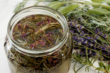 Herbs infused vinegar in open jar. Thieves vinegar, alternative medicine remedy with wormwood,...