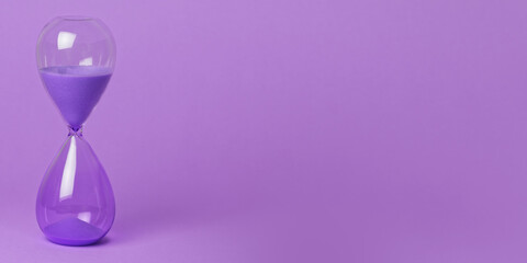 Purple hourglass on purple background banner. Passing time or deadline concept.