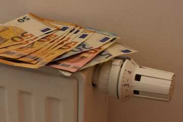 Euro money banknotes on heating radiator battery with temperature regulator. Expensive heating...