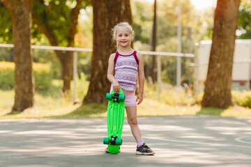 Pretty little girl learning to skateboard outdoors on beautiful summer day