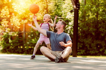 Happy father and child daughter outside at basketball court.