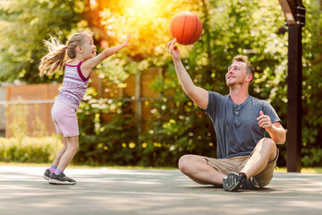 Happy father and child daughter outside at basketball court.