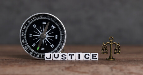  White cube with 'JUSTICE' text and a compass. Business concept with miniature.
