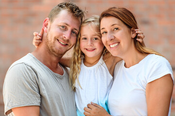 Happy young family in a urban background. Father, mother and little daughter.