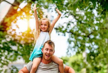 Happy Father and little daughter on shoulder outside on back street