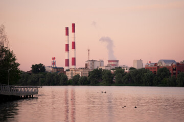 Obraz premium A thermal power plant at dawn. Reflection of pipes and cooling towers in the water. Kazan, Russia. The embankment of Kaban Lake.