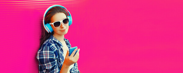 Portrait of young woman in headphones listening to music with smartphone on background