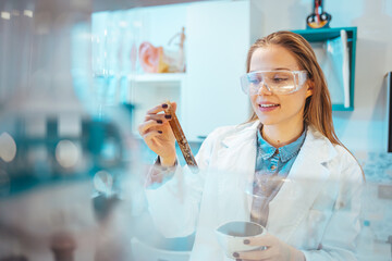 Beautiful Female Scientist Wearing Protective Goggles Mixing Chemicals in a Test Tube in a Lab....