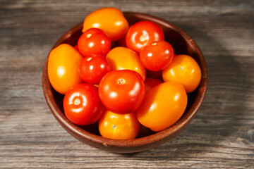 wooden bowl with red and yellow ripe tomatoes on a dark background. view from above