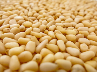 Close-up of scattered peeled pine nuts in the frame. Cedar fruits. Gifts of nature. Healthy nutrition, vitamins, vegetable protein, vegetable fats, healthy lifestyle, healthy snack