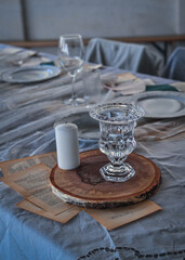 Close up candle and glass goblet on  stand made of wood in minimal eco-friendly style. Fashionable table setting