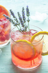 Summer cocktail or mocktail, cold drink with lemon and lavender, party lemonade with ice on a blue background, a close-up