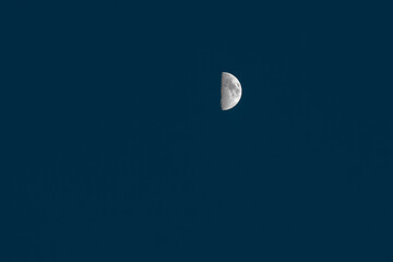 Crescent moon small against dark blue evening sky natural light background