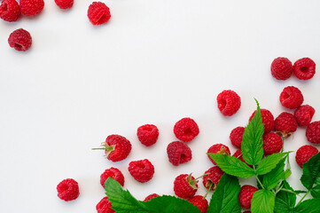 Ripe juicy fresh raspberries with green leaf on white background flat lay top view. Raspberry pattern. Organic raspberries, healthy food, vitamins, summer berry fruit background. Raspberry harvest