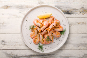 boiled shrimp with lemon on a white plate top view on white wooden table