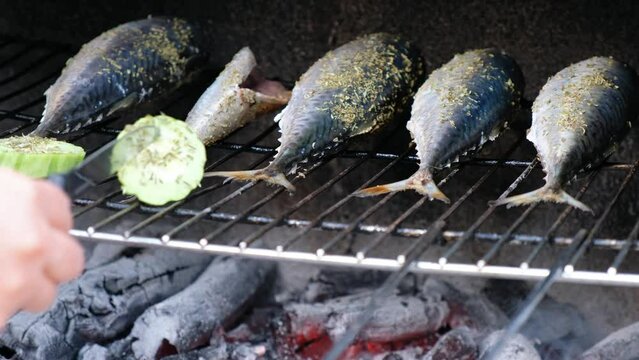Cooking mackerel fish with vegetables on a grill barbecue