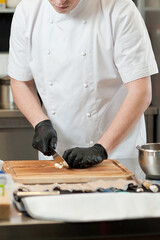 The cook cuts vegetables with a knife to prepare the dish. Cutting vegetables.