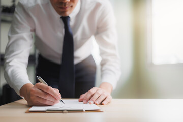 Closeup Businessman signing a doucument agreement on the table with pen. Corporate man,accountant working in office