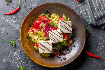 Greek salad with feta and fresh vegetables with balsamic sauce on grey table top view