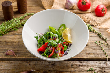 Vegetable salad with tomatoes and cucumbers on old wooden table