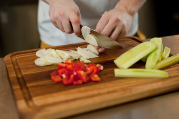 The cook cuts vegetables with a knife to prepare the dish. Cutting vegetables.
