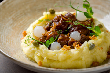 Beef cheeks with mashed potatoes on brown table macro close up