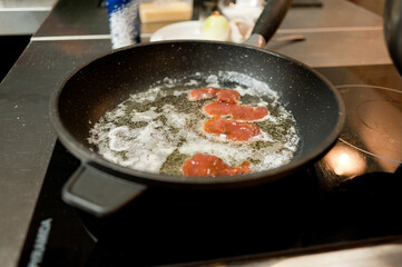 Cook fries meat in a pan with vegetables.