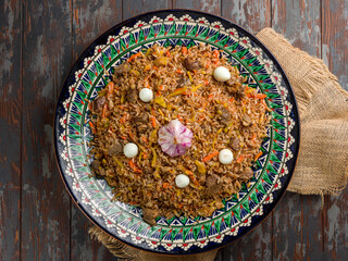 pilaf with beef, eggs, carrot on beautiful uzbek plate top view