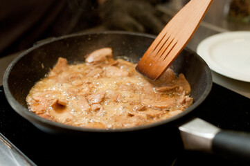Cook fries meat in a pan with vegetables.