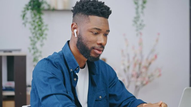 Inspired black young man watching lesson on laptop, studying online, smiling