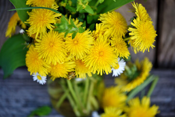 Bouquet of dandelion flowers, yellow wildflowers on old wooden table. Close-up