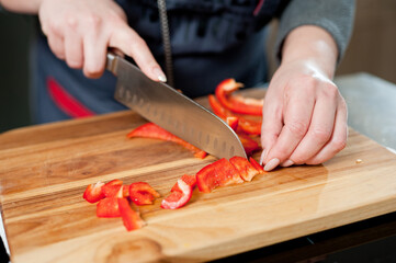 The cook cuts vegetables with a knife to prepare the dish. Cutting vegetables.
