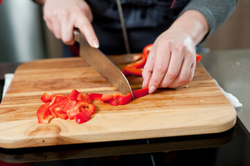 The cook cuts vegetables with a knife to prepare the dish. Cutting vegetables.