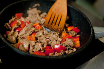 Cook fries meat in a pan with vegetables.